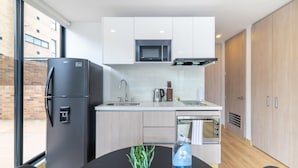 A modern kitchen with a refrigerator, microwave, sink, and wooden cabinets. - w Lovely Loft With Terrace in Santa Ana (Bogotá)