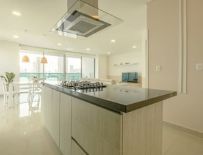 A modern kitchen with a large island, built-in appliances, and a city view.