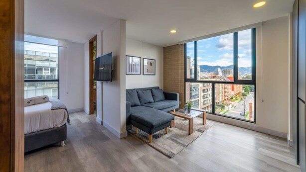A modern living room with a sofa, a coffee table, and a TV mounted on the wall. - w Classy Loft in Pasadena (Bogotá)