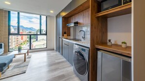 A modern kitchen with a large window, a washing machine, and a compact refrigerator. - w Classy Loft in Pasadena (Bogotá)