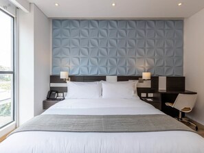 A modern hotel room with a large bed, two bedside tables, a desk, and a chair. - Homey Loft in San Patricio (Bogotá)