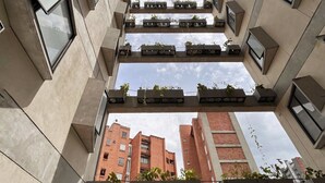 A high-rise building with multiple balconies, each with potted plants. - Bright Loft in Laureles (Medellín)