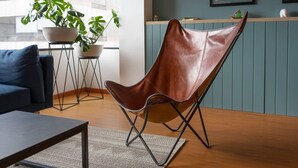 A modern living room with a leather chair, a coffee table, and a rug.