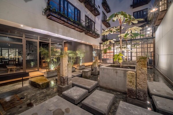 A modern indoor courtyard with stone steps, potted plants, and a visible gym sign. - Amazing Loft In Candelaria (Bogotá)