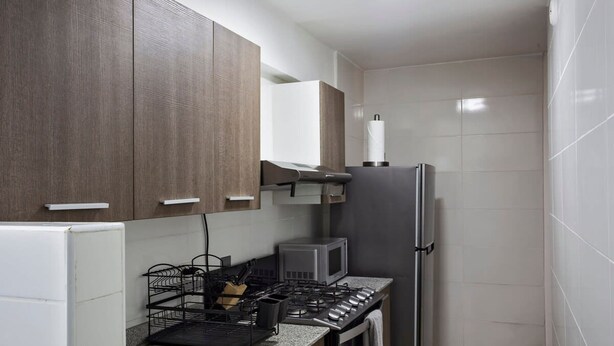 A compact kitchen with a stainless steel sink, a microwave, and a refrigerator. - Modern 2BR In La Cresta (Panama City)