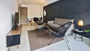A modern living room with a sofa, a coffee table, a TV, and a lamp. - Modern 2BR In La Cresta (Panama City)
