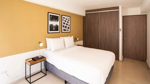 A hotel room with a bed, a bedside table with a lamp, a wardrobe, and two framed pictures on the wall. - Modern 2BR In La Cresta (Panama City)