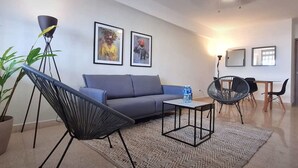 A modern living room with a grey sofa, black chairs, a coffee table, and a potted plant. - Modern 2BR In La Cresta (Panama City)