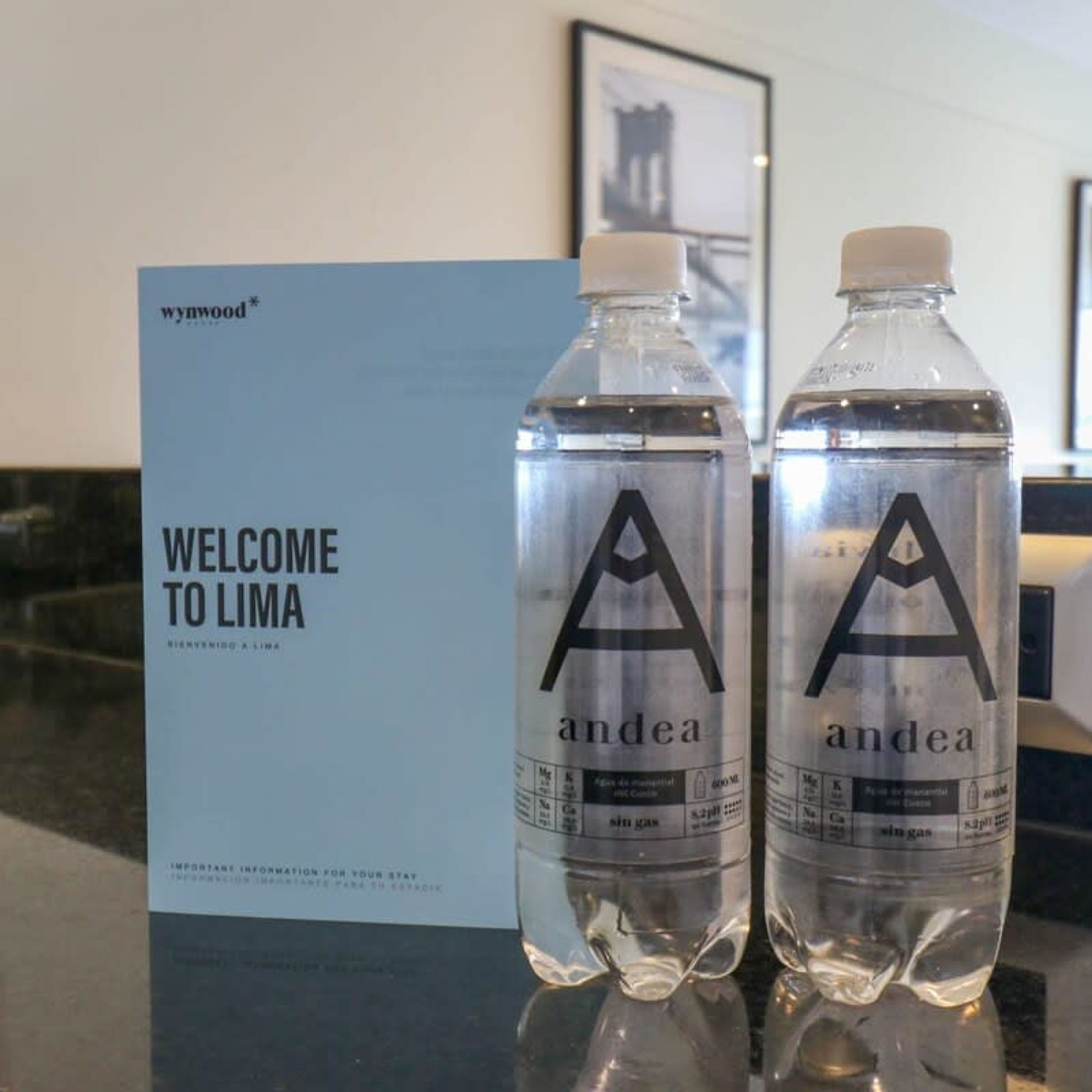 Two water bottles labeled 'andea' on a table with a 'WELCOME TO LIMA' sign in the background.