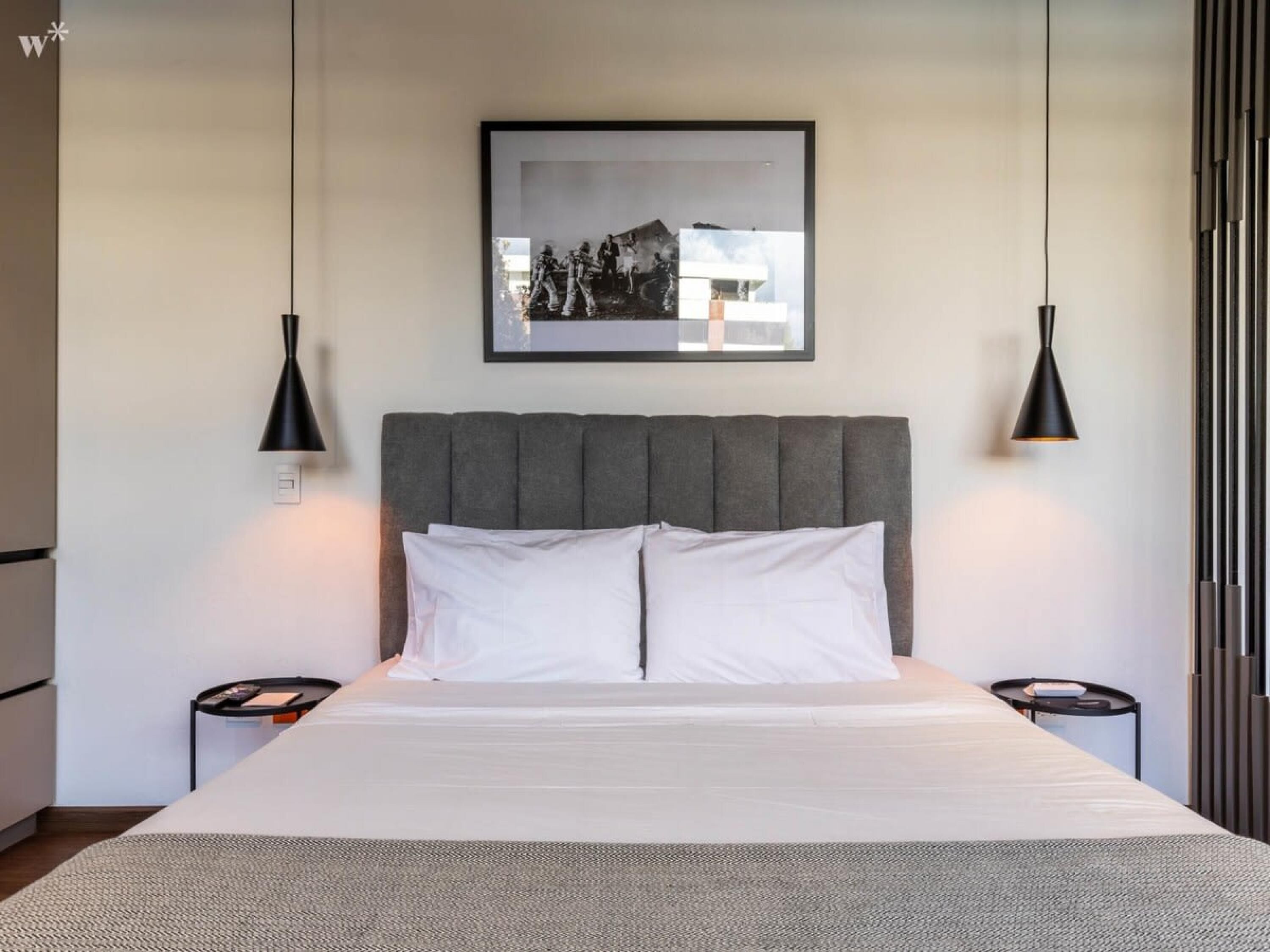 Une chambre à coucher moderne avec un grand lit, deux tables de chevet et un tableau encadré au-dessus du lit.