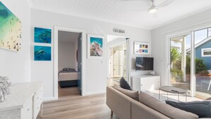 A modern living room with a sofa, a TV, and artwork on the walls. - 6 Beach Rd Goolwa South (Goolwa South)
