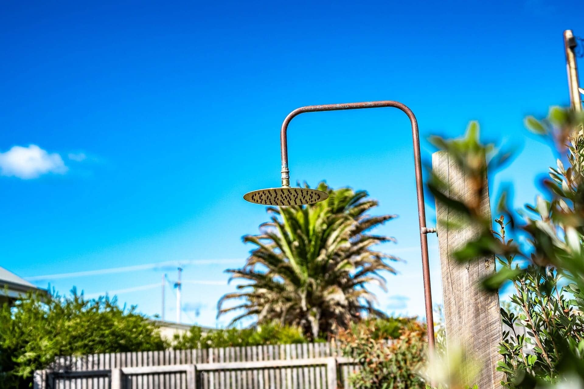 Eine Straßenlaterne mit einem gebogenen Metallausleger und einer runden Leuchte, vor blauem Himmel.