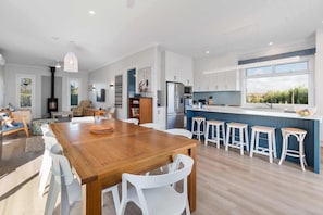 A modern kitchen with a central island, bar stools, and a large window.