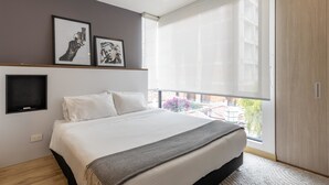 A modern bedroom with a large bed, a view of the city through a large window, and two framed pictures on the wall. - w Splendid Loft in Santa Ana (Bogotá)