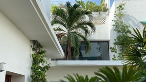 Un bâtiment moderne à deux étages doté d’une cour intérieure agrémentée de palmiers et de diverses plantes.