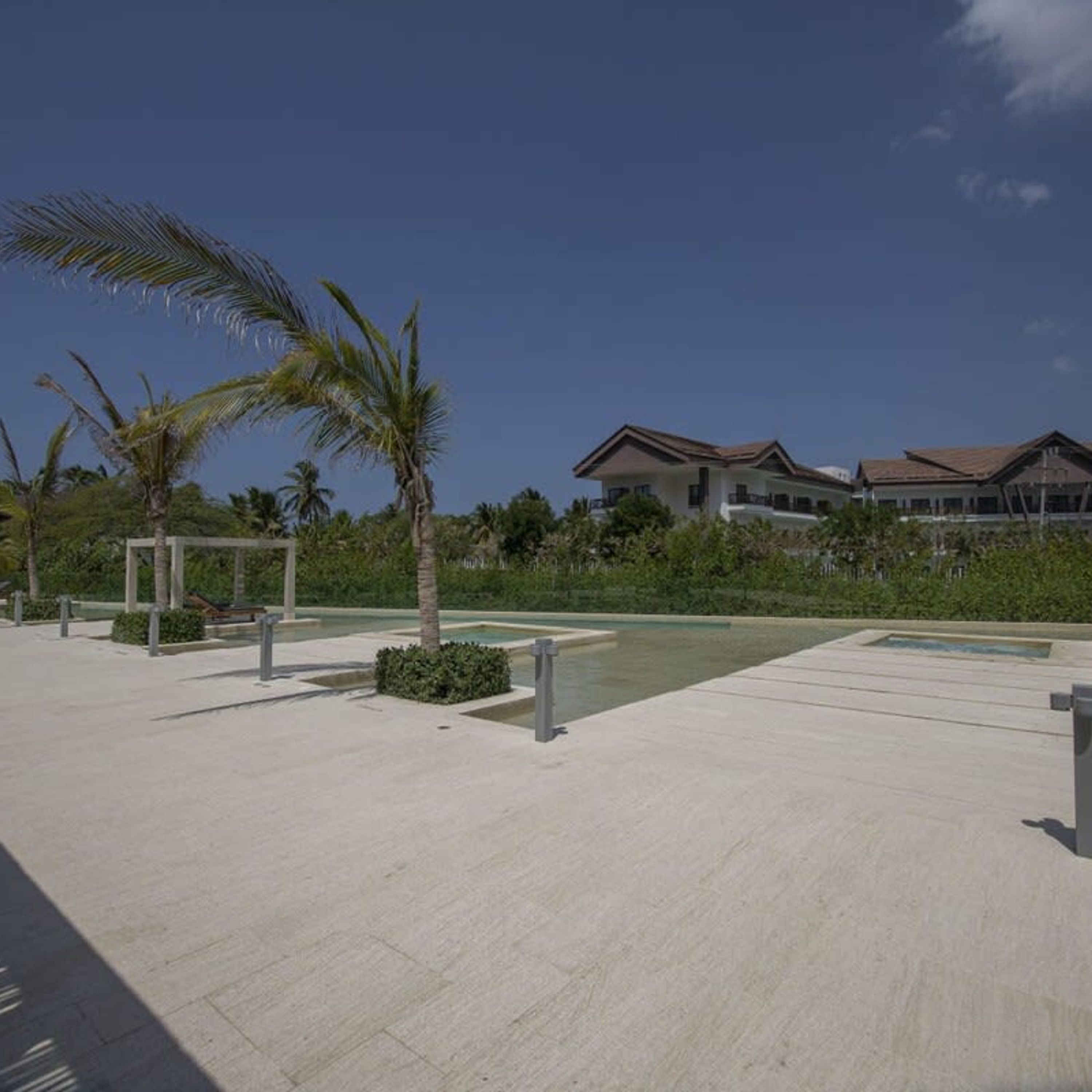 A resort area with a pool, palm trees, and modern buildings.