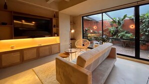 A modern living room with a sofa, a TV, and a dining area with chairs and a table.