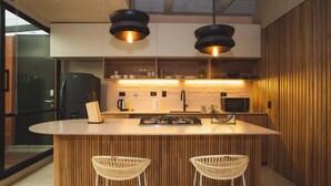 A modern kitchen with a central island, two bar stools, and pendant lighting.