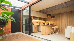 A modern kitchen with a glass door leading to a dining area, a wooden counter, and a bar stool.