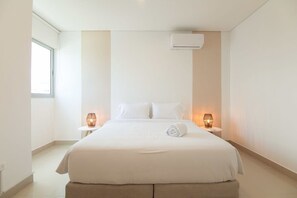 A modern hotel room with a large bed, two bedside tables with lamps, a window, and an air conditioning unit. - w Modern 3BR w AC in Cartagena (Cartagena)