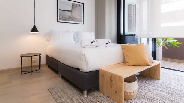 Une chambre moderne avec un lit, une table de chevet, un banc et une grande fenêtre.