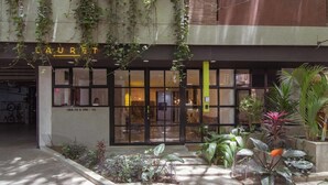 Un bâtiment avec une enseigne indiquant « LAURET » et une entrée en verre. On y voit des plantes et un bac à fleurs en béton devant.