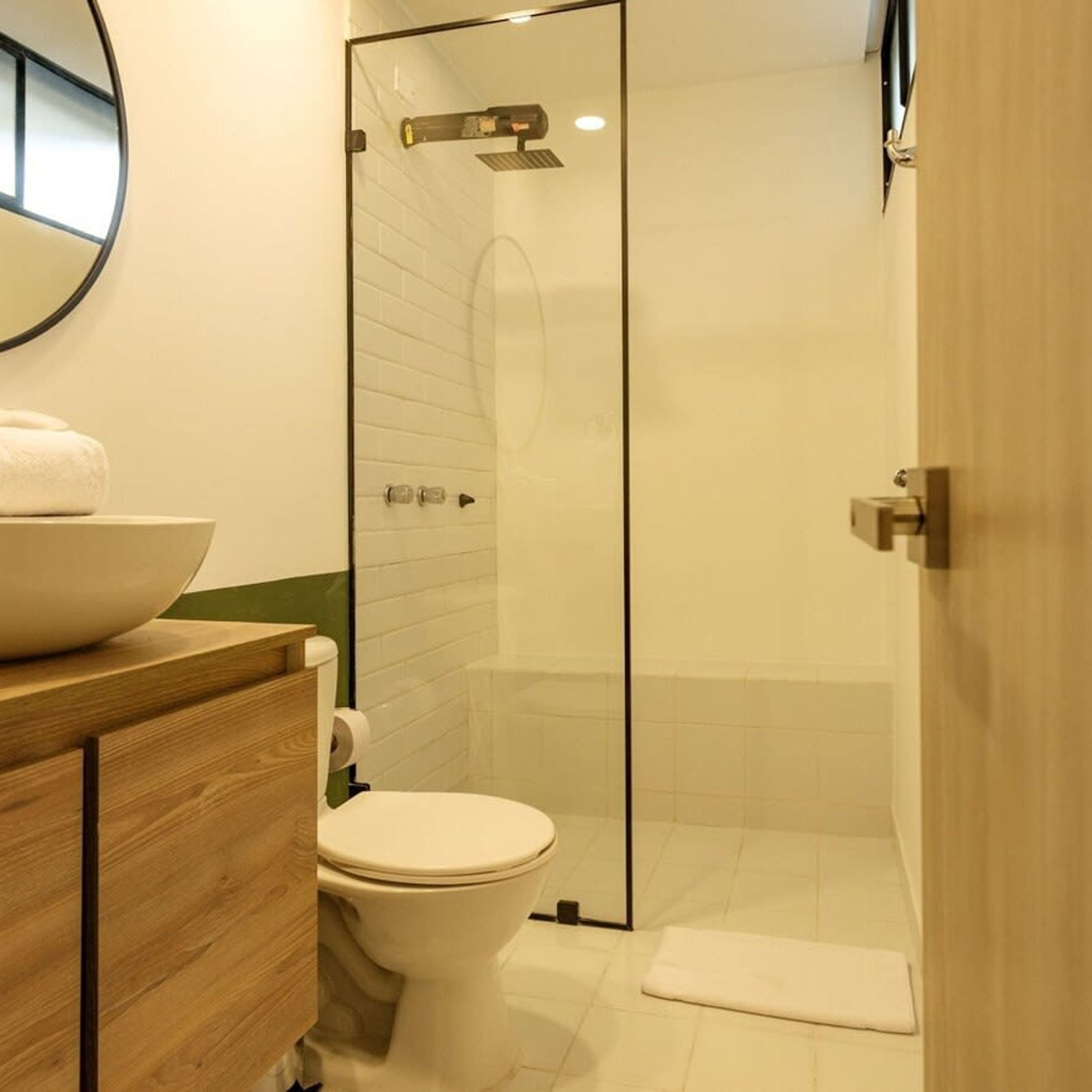A modern bathroom with a glass shower enclosure, a wooden vanity, and a white toilet.