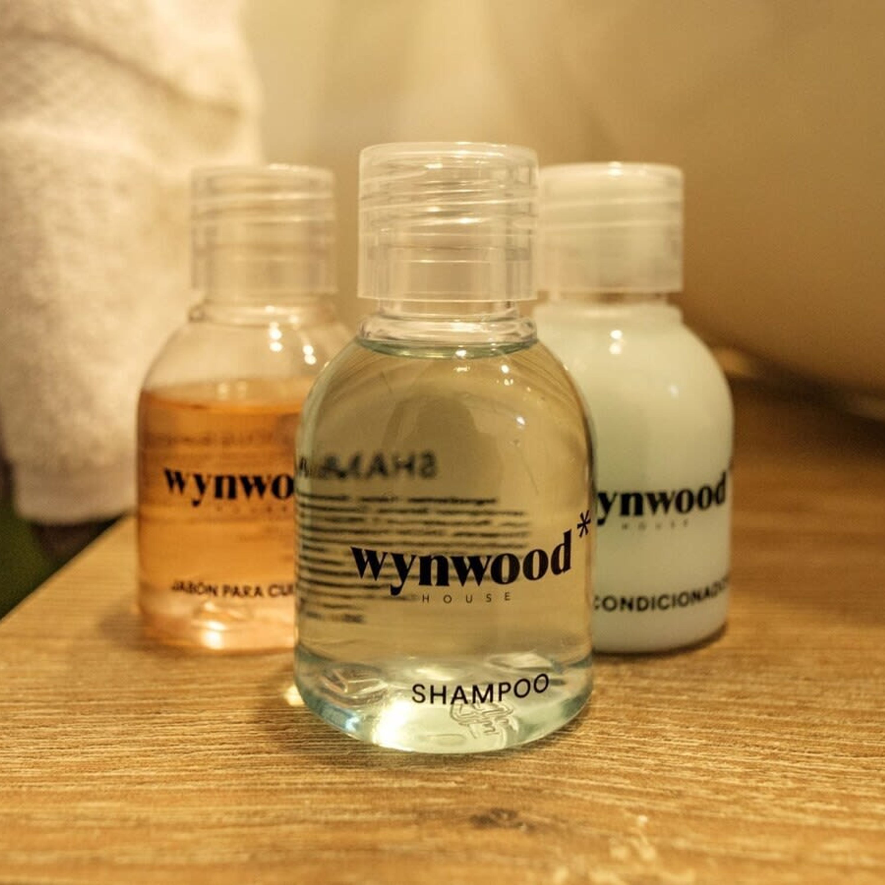 Drei Flaschen Shampoo von Wynwood House auf einer Holzoberfläche.
