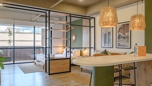 A modern interior with a central island, seating area, and a glass partition separating the living space from the dining area.