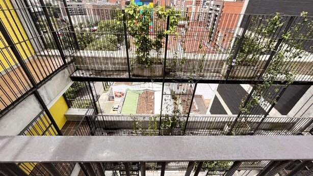 A multi-story building with balconies, a view of a cityscape, and a mountain range in the background. - w Lovely Loft in Laureles (Medellín)