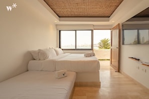 A modern bedroom with two beds, a large window, and a view of the city.