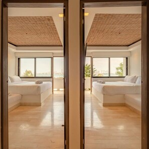 A modern hotel room with two white sofas, large windows, and a wooden ceiling.