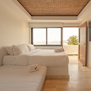 A modern hotel room with two beds, a large window, and a view of the city.