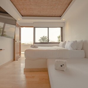 A modern bedroom with a large window, a bed, and a small table.