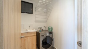 A compact laundry room with a washing machine, a sink, and a drying rack. - w Classy 1BR in Chapinero (Bogotá)