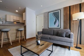 A modern living room with a grey sofa, wooden coffee table, and a remote control. - w Dreamy 1BR in Barranco (Lima)
