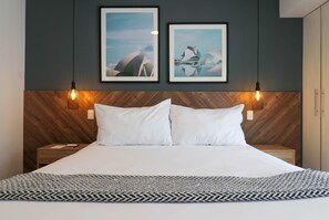 A hotel room with a large bed, two framed pictures on the wall, and a wooden headboard. - w Dreamy 1BR in Barranco (Lima)