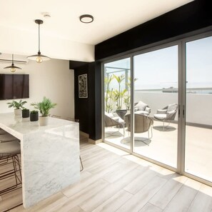 A modern kitchen with a marble countertop and a dining area with chairs and a table. - w Artistic 1BR in Barranco (Lima)