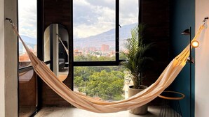 A room with large windows, a hammock, a potted plant, and a hanging light fixture. - Trendy Loft With Balcony in Laureles (Medellín)