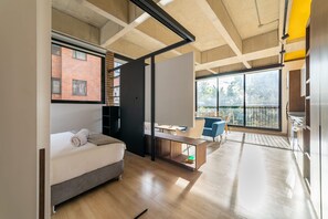 A modern hotel room with a bed, a desk, and a balcony with a view of the city. - Splendid Loft in Parque 93 (Bogotá)