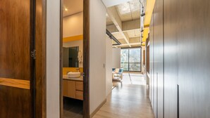 A modern hallway with a wooden door, a bathroom with a sink and mirror, and a view of a balcony. - Splendid Loft in Parque 93 (Bogotá)