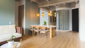 A modern living room with a wooden dining table, chairs, a sofa, and pendant lights. - w Stunning 3BR With AC in Laureles (Medellín)