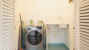 A laundry room with a washing machine, a sink, and a broom. - w Stunning 3BR With AC in Laureles (Medellín)
