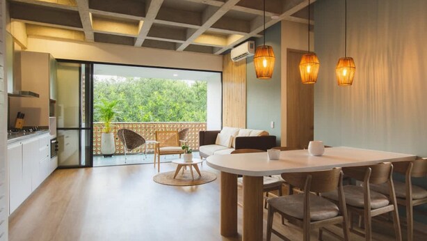 A modern kitchen with a dining area, large windows, and a balcony with a view of greenery. - w Stunning 3BR With AC in Laureles (Medellín)