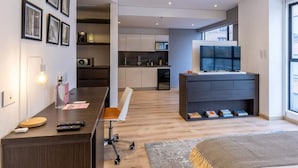 A modern living room with a dark wooden desk, a white chair, and a large flat-screen TV on a dark console. - Perfect Loft in San Patricio (Bogotá)