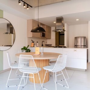 A modern kitchen with a central island, white chairs, and stainless steel appliances. - w Amazing 2BR w/ AC in Laureles (Medellín)