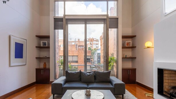 Una sala de estar moderna con un ventanal grande, un sofá, una mesa de centro y una chimenea.