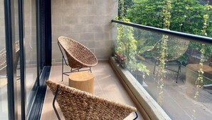 Een balkon met twee rieten stoelen en een klein houten krukje.