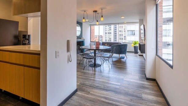 A modern kitchen with wooden cabinets, a coffee machine, and a dining area with a round table and chairs.