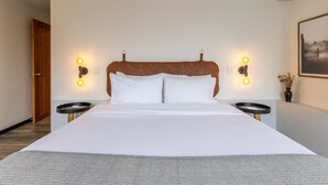 A hotel room with a large bed, two bedside tables, and wall-mounted reading lights.